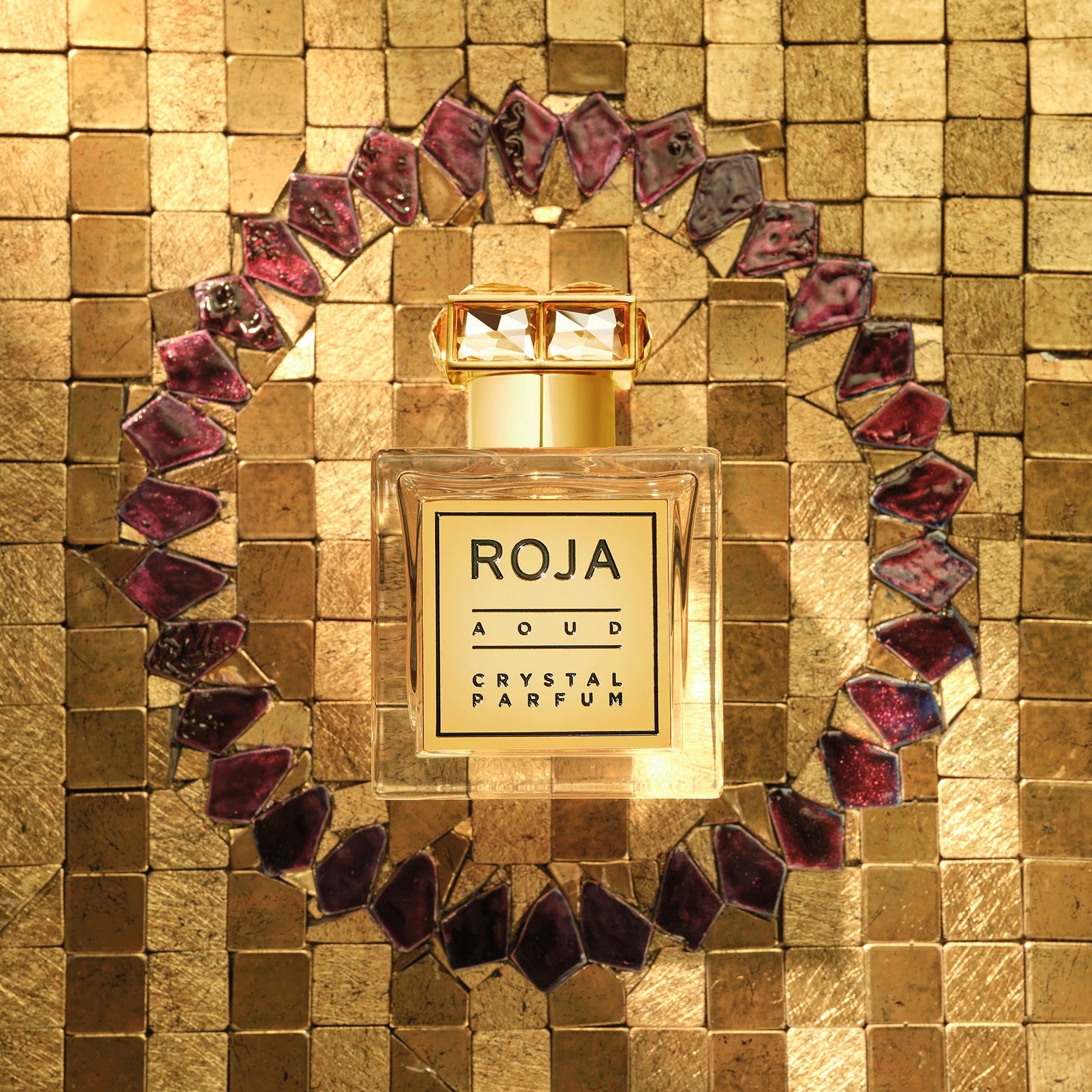 Roja Aoud Crystal Parfum bottle on a textured gold background