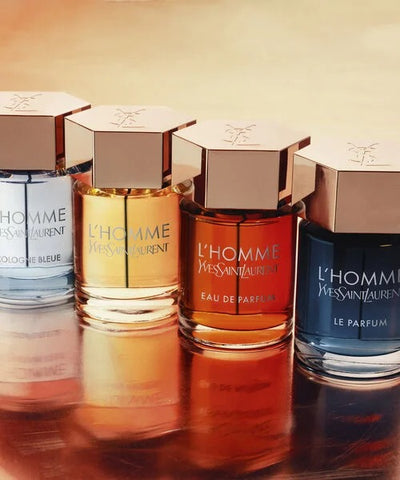 Four bottles of Yves Saint Laurent men's perfume on a reflective surface with a warm background.